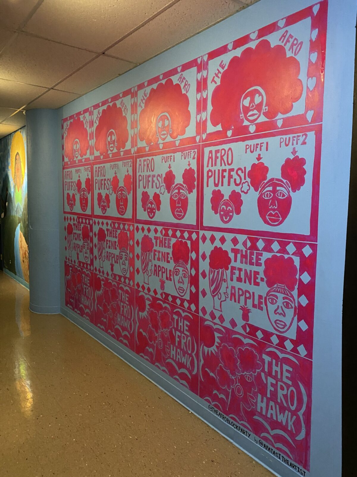 Pink mural with Afros on a blue wall in a hallway.